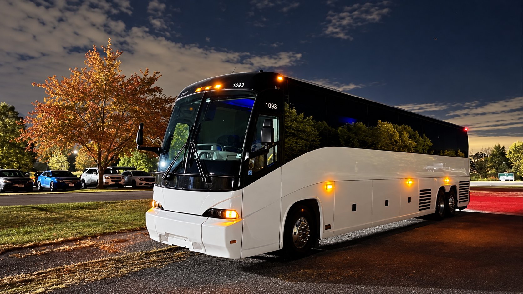 White full-size motorcoach parked at night